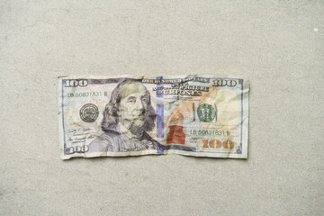 a crumpled 100 dollar bill, currency concept, isolated on grey background.
