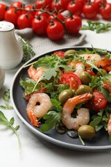 Delicious shrimp salad with tomatoes and olives on white marble table, closeup