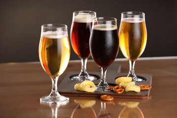 Glasses with different types of beer and snacks on table