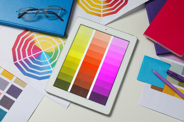 Designer's workplace with tablet, different palettes and stationery on white table, flat lay