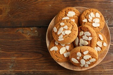 Tasty cookies with almond flakes on wooden table, top view. Space for text