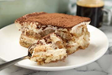 Piece of tasty tiramisu on white marble table, closeup