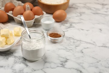 Baking powder in jar and other products on white marble table, closeup. Space for text