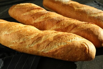 Freshly baked baguettes on black table, closeup