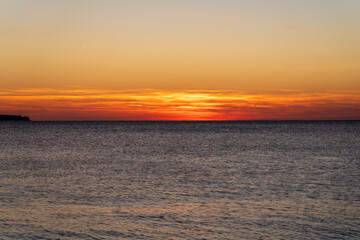Piran, Slovenia - November 3, 2024: Sunset against the backdrop of a calm sea. The sun goes down behind the sea horizon.
