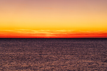 Piran, Slovenia - November 3, 2024: Sunset against the backdrop of a calm sea. The sun goes down behind the sea horizon.