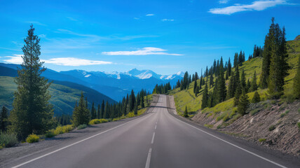 Fototapeta premium A scenic view of a winding road through lush green hills under a clear blue sky, with majestic mountains in the background.