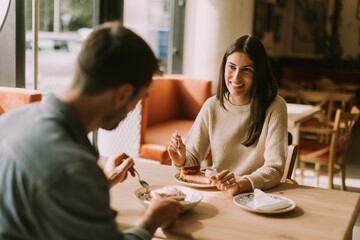 A joyful couple enjoys coffee and pastries in a cozy cafe during a sunny afternoon