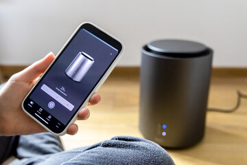 Woman setting up a heater through the smart home app. Miniature heater. Temperature control.