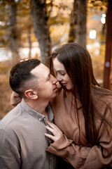 a young couple guy with a girl in autumn in a cafe in brown and orange tones on an outdoor terrace hugging and kissing, love or Valentine's day