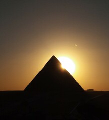 sillouete  pyramid .sunset behind pyramids of giza  egypt. clear sky and half sun