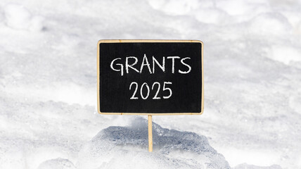 Planning grants 2025 new year symbol. Concept words Grants 2025 on beautiful yellow chalk blackboard. Beautiful white snow background. Business grants 2025 new year concept. Copy space.