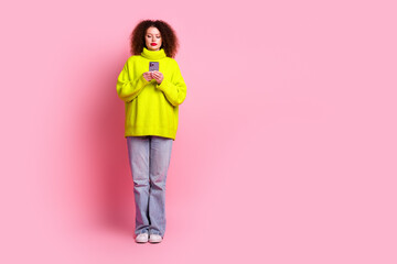 Full length photo of lovely young lady hold telephone dressed stylish yellow garment isolated on pink color background