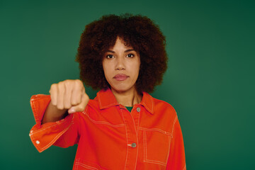 A young African American woman in casual attire showcases her emotions passionately on a vibrant green background.