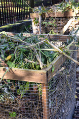 Compost bins for plant waste are set up in a garden to support eco-friendly recycling. Organic...