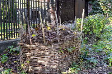 Compost bins for plant waste are set up in a garden to support eco-friendly recycling. Organic...