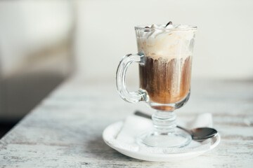 Close-up of an Irish coffee with whipped cream on a wooden table