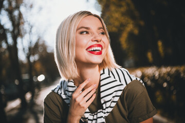 Photo of pretty young blonde woman look wondered have fun wear khaki clothes tied shoulders sweater walk outside urban city park