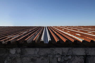 Rusty roof against a clear blue sky. old rust-eaten tin zinc roof. old rusty corrugated metal roof...