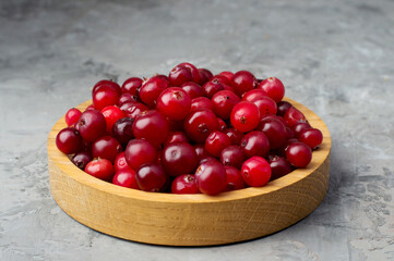 Cranberries in a wooden bowl on a dark background. Healthy food, vitamins, antioxidants.