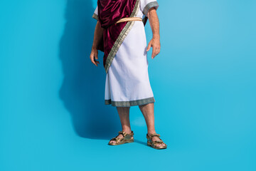 Cropped photo of old man legs sandals dressed greek god emperor actor costume isolated on blue...