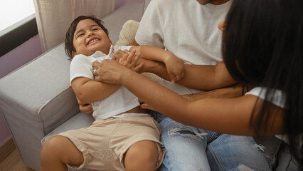 Family enjoying playful moment with child in living room of their home implying love and...