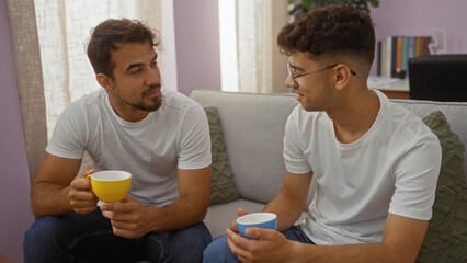 Father and son having coffee while talking in a cozy living room, showcasing family love and bonding between two hispanic men indoors