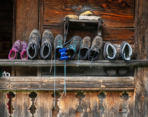 Wanderschuhe  in unterschiedlichen Größen und Farben  und ein Fernglas vor einer antiken Holzwand