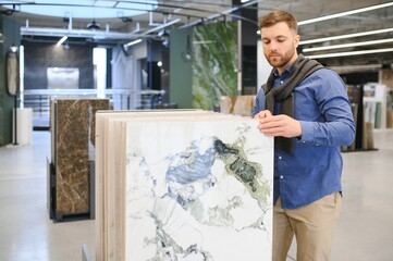 Young man choosing tiles at building market