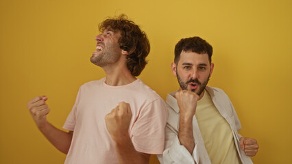 Men celebrating together against a yellow background, showcasing friendship and joy in an isolated...