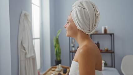 Beautiful young woman with towel in hair and robe standing in a cozy spa wellness center room