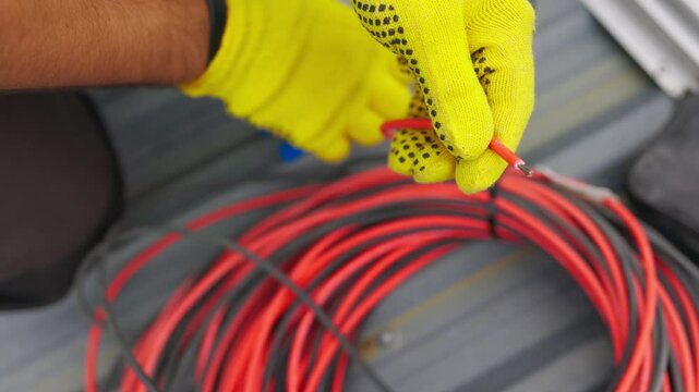 Electrician technician worker with wire stripper plier prepares the electric cable in electrical system. Electrician installing wires. A professional electrician removes electrical insulation.