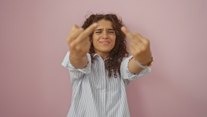 Hispanic woman showing rude gesture with both hands against a pink isolated background expressing...