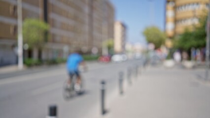 Blurred cyclist riding on an urban street with buildings and cars in the background on a sunny day