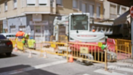 Blurred construction workers in an outdoor site with machinery and yellow barriers on a sunny day creating vibrant bokeh effects.