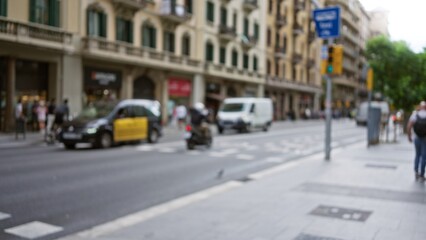 Blurry street scene in barcelona showcasing taxis, pedestrians, motorcycles and urban architecture in a defocused, vibrant european city atmosphere.