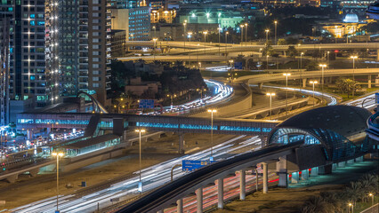 Fototapeta premium Futuristic building of Dubai metro and tram station and luxury skyscrapers behind night timelapse