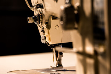 Close-up of the sewing head of a modern industrial sewing machine with a black background