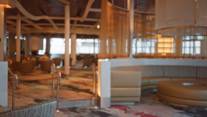 Blurred luxurious cruise interior hall with defocused seating and bokeh effect, creating an elegant and sophisticated atmosphere through soft lighting and modern design.