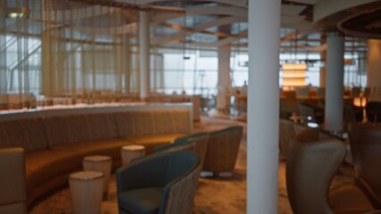 Dimly lit blurred luxury restaurant interior with comfortable chairs, elegant tables, and soft lighting evoking a sophisticated ambiance ideal for upscale dining.