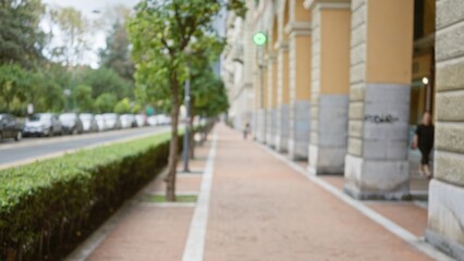 Blurred city street scene in la spezia, italy, featuring a woman walking on a sidewalk with trees, cars, and historic architecture in the background.