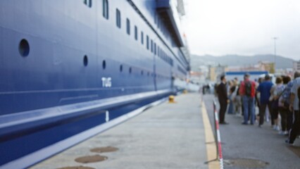 People standing at cruise port, blurred and out of focus, with large ship in background in bokeh...