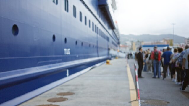 People standing at cruise port, blurred and out of focus, with large ship in background in bokeh effect, creating a defocused outdoor setting with vibrant crowd atmosphere.
