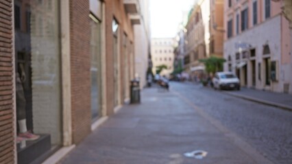 Street view in rome captures blurred town scene with focus on architecture and cobblestone road under bright sunlight.