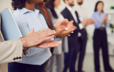 Multicultural group of business people clapping, hands close-up. Successful team standing in a row...