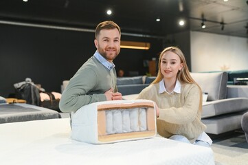 Couple buying new bed with orthopedic mattress in furniture store
