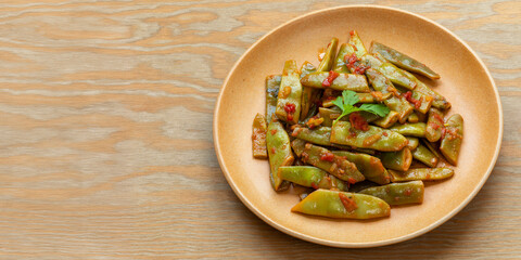 Homemade taze fasulye - Turkish style stewed runner beans on a plate. Popular meze and summer food. Banner with space for text. 