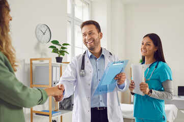 Friendly man doctor and woman nurse meeting a new patient together. Happy, smiling man in a white...