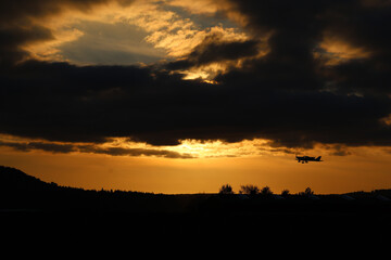 Obraz premium small motor plane taking off at sunset in dramatic scenery of dark autumn clouds