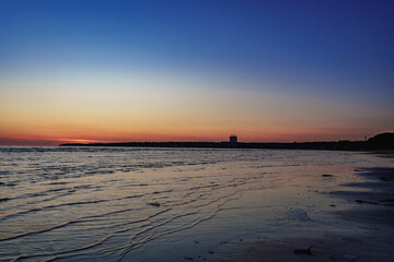 Serene beach at sunset with calm waves and distant horizon